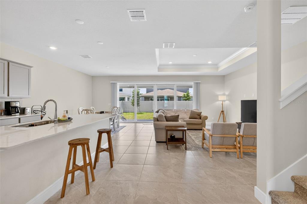 An open-concept kitchen and living area features tile flooring, a breakfast bar, and sliding doors — 6036 FOREST PERCH DRIVE, ST CLOUD, FL