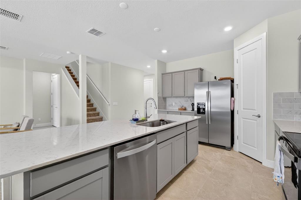 A kitchen features gray cabinets, stainless steel appliances, and a white quartz-topped island — 6036 FOREST PERCH DRIVE, ST CLOUD, FL