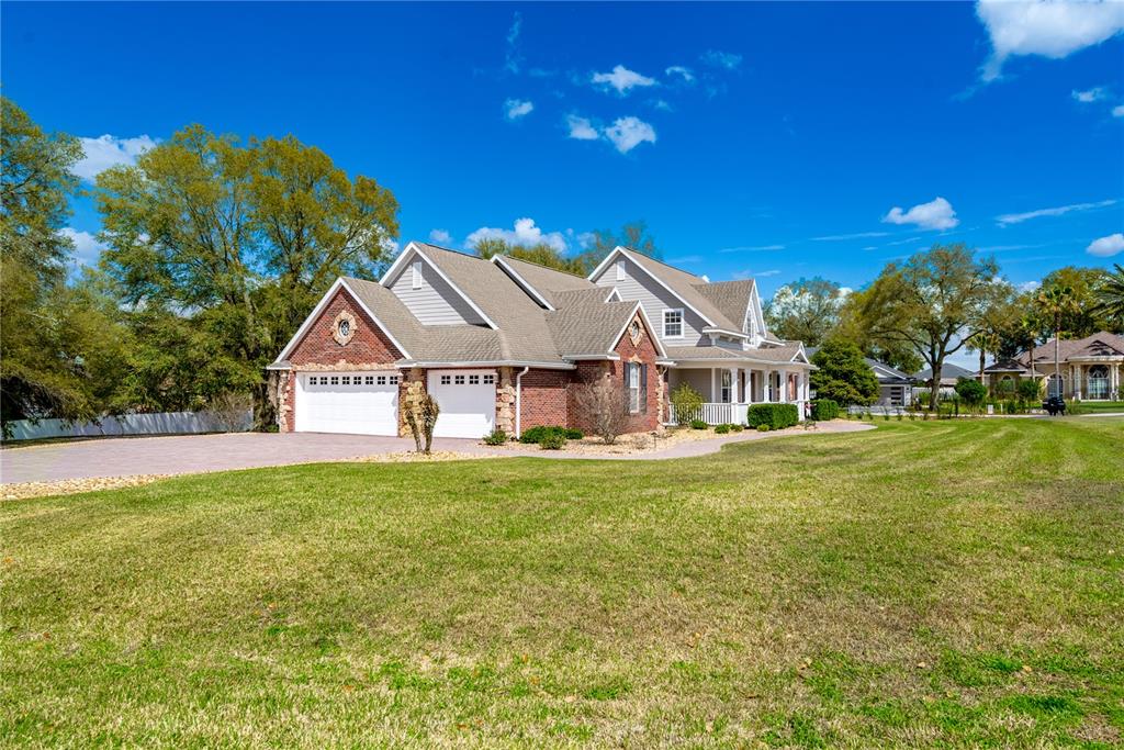 A brick and gray-sided house with a multi-car garage sits on a large grassy lot — 5795 SW 43RD PLACE, OCALA, FL