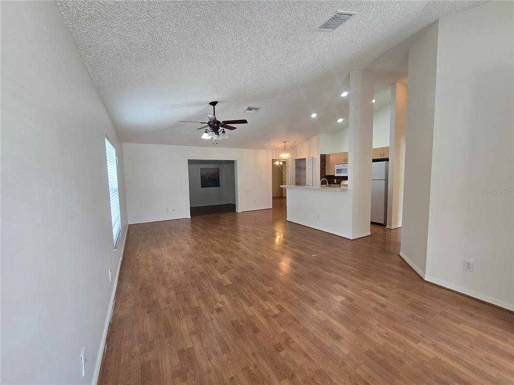 An open-concept living area features wood-look flooring, a kitchen with light cabinets, and a pantry — 1926 29TH AVENUE N, ST PETERSBURG, FL