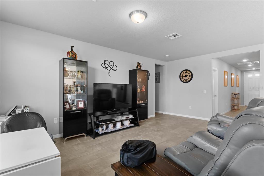A living room features tile flooring, a television on a stand, and gray leather recliners — 1502 BRANCHWOOD LANE, AUBURNDALE, FL