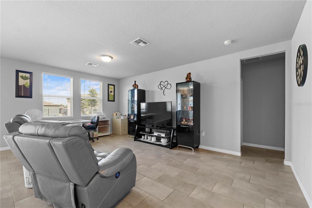 A living room features gray walls, tile flooring, a television console, and a leather recliner — 1502 BRANCHWOOD LANE, AUBURNDALE, FL