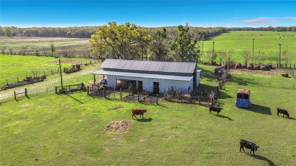 An aerial view shows a large fenced pasture with a pole barn and a lighted arena — 855 NE 107TH ROAD, OXFORD, FL