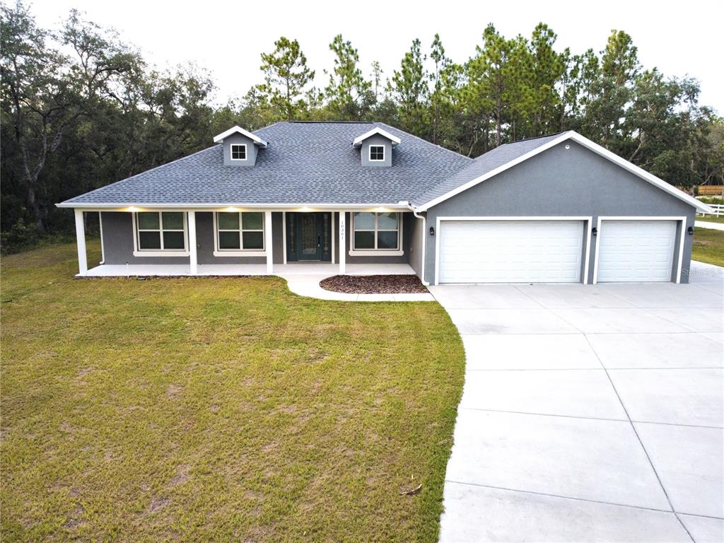 A gray single-story house with a white-trimmed porch, two dormer windows, and a three-car garage — 10361 THRASHER AVENUE, WEEKI WACHEE, FL