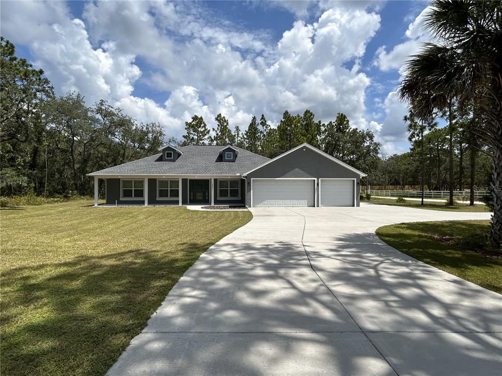 The exterior of a gray house features a covered patio with white columns and trim — 10361 THRASHER AVENUE, WEEKI WACHEE, FL