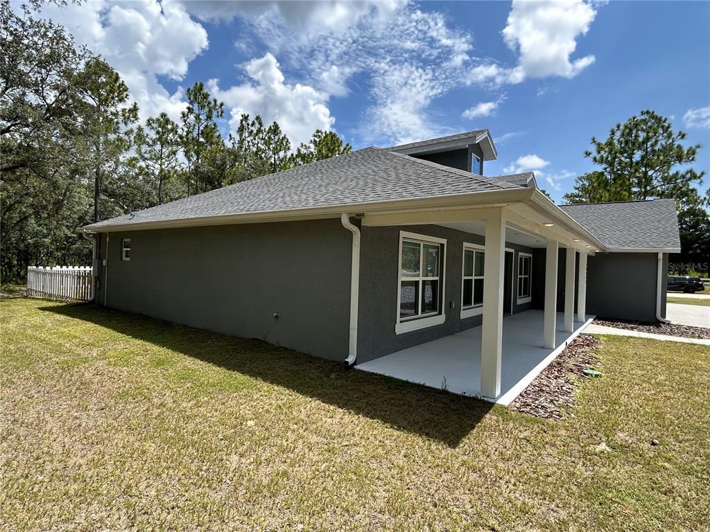 The exterior of a gray house features a covered patio with white columns and trim — 10361 THRASHER AVENUE, WEEKI WACHEE, FL