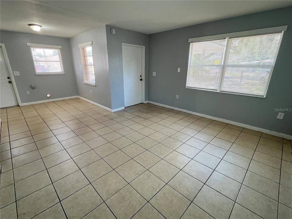 An empty room with light gray walls, tiled flooring, and multiple windows and doors — 1997 5TH STREET NE, WINTER HAVEN, FL