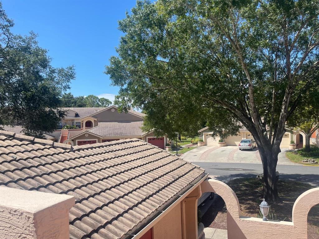 An elevated view shows a tiled roof overlooking a residential street with houses and trees — 7786 SUGAR BEND DRIVE UNIT 7786, ORLANDO, FL