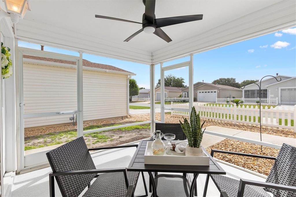 A screened-in porch features a ceiling fan, patio furniture, and views of a neighborhood street — 2014 JOHNSON COURT, THE VILLAGES, FL