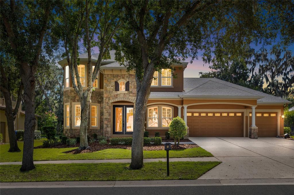 A two-story house with a stone facade, a three-car garage, and a concrete driveway — 15910 TERNGLADE DRIVE, LITHIA, FL