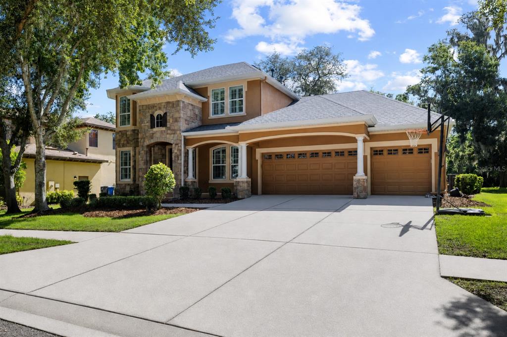 A two-story house with a stone facade, tan stucco, and a three-car garage — 15910 TERNGLADE DRIVE, LITHIA, FL