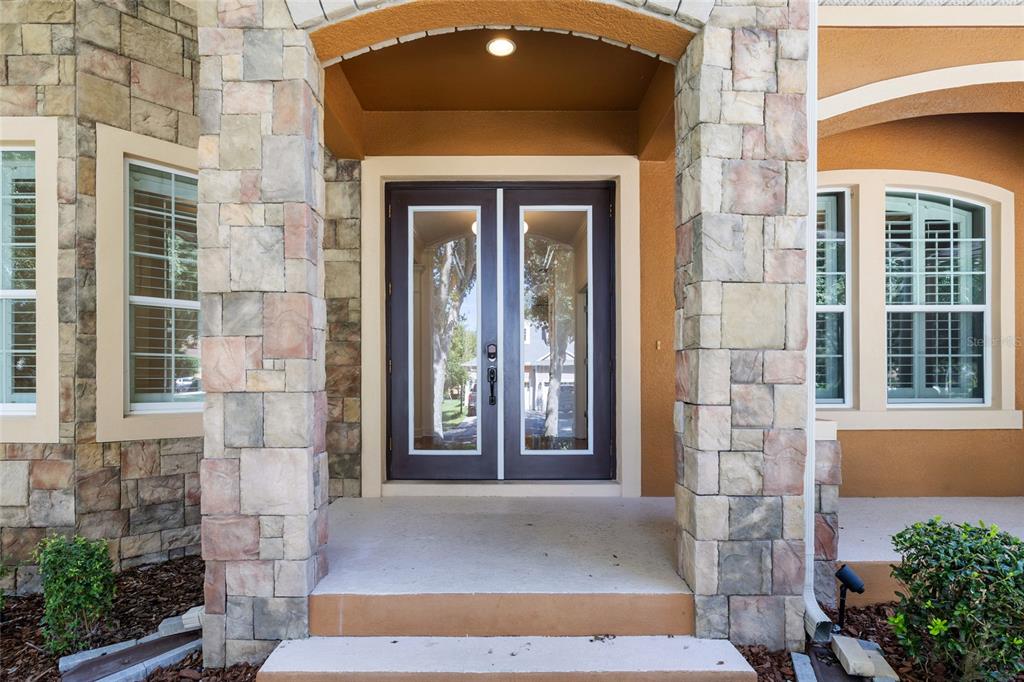 A stone-clad entryway features a double glass door under a recessed archway with concrete steps — 15910 TERNGLADE DRIVE, LITHIA, FL