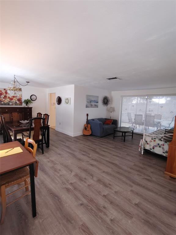 An open-concept living and dining area features wood-look flooring, a blue sofa, and sliding doors — 3425 RICHBORO DRIVE, HOLIDAY, FL