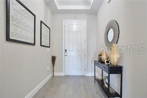 A bright entryway features light wood-look flooring, a white front door, and a console table — 3160 FIRETHORN CIRCLE, DAYTONA BEACH, FL