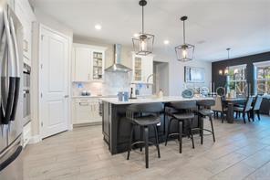 A modern kitchen features white cabinets, a dark island with bar stools, and pendant lighting — 3160 FIRETHORN CIRCLE, DAYTONA BEACH, FL