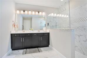 A bathroom features a dark wood vanity, a large mirror, and a glass-enclosed marble shower — 3160 FIRETHORN CIRCLE, DAYTONA BEACH, FL