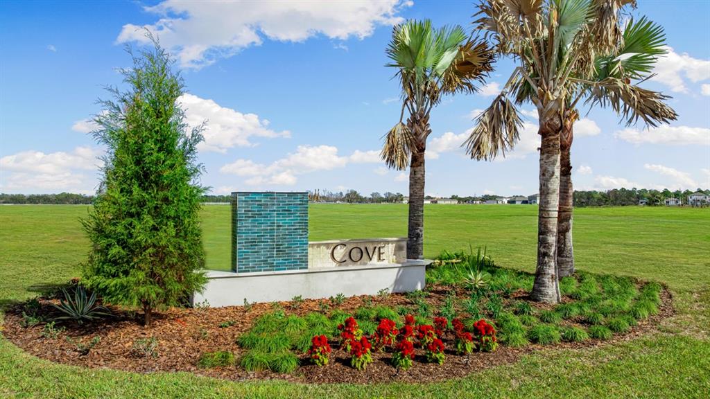 A stone monument sign labeled Cove sits in a landscaped garden with palm trees — 9344 CHISWELL TRAIL, PALMETTO, FL