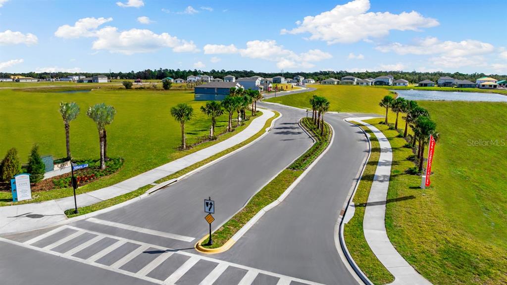 An aerial view shows a paved road leading into a residential neighborhood with palm trees — 9344 CHISWELL TRAIL, PALMETTO, FL