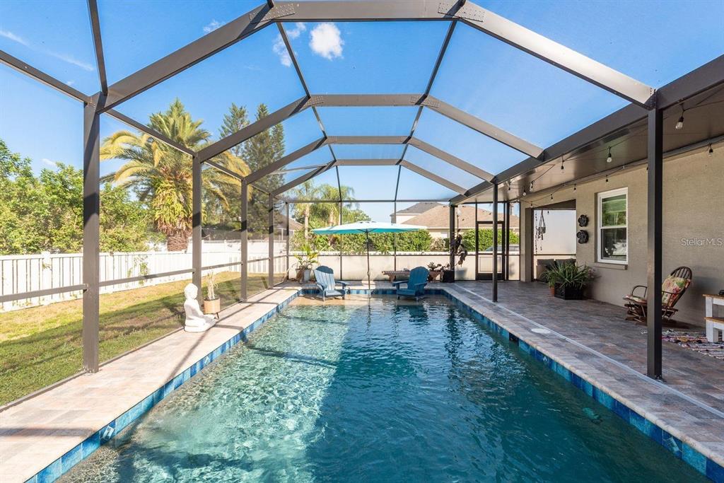 A screened-in swimming pool with a patio and lounge chairs in a backyard setting — 1810 WINSLOE DRIVE, TRINITY, FL