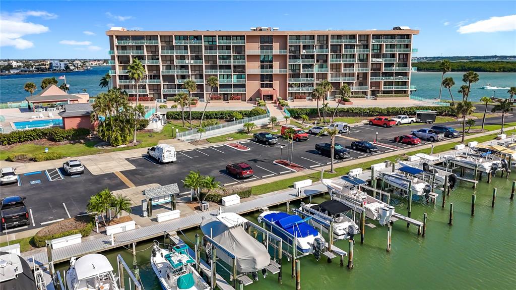 An aerial view shows a multi-story apartment building, a parking lot, and a boat dock — 1 KEY CAPRI UNIT 201E, TREASURE ISLAND, FL