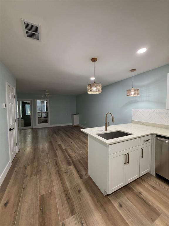 A kitchen with white cabinets and a light-colored countertop opens into a spacious living area — 230 MEDALLION BOULEVARD UNIT C, MADEIRA BEACH, FL