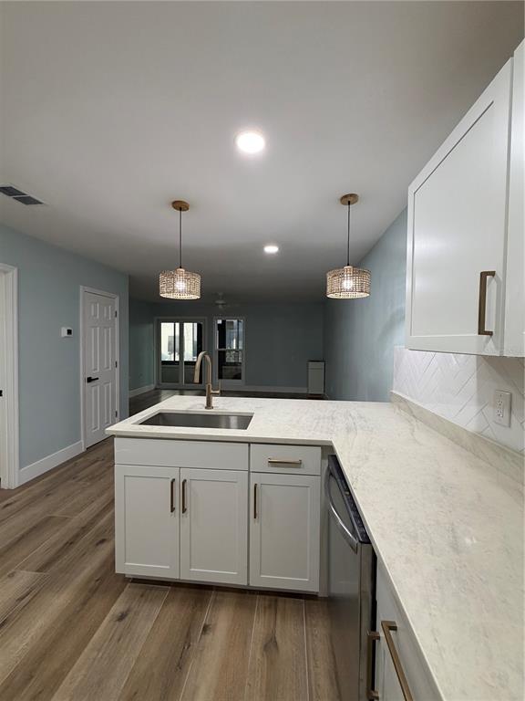 A kitchen features white cabinets, a stone countertop, a stainless steel sink, and pendant lights — 230 MEDALLION BOULEVARD UNIT C, MADEIRA BEACH, FL