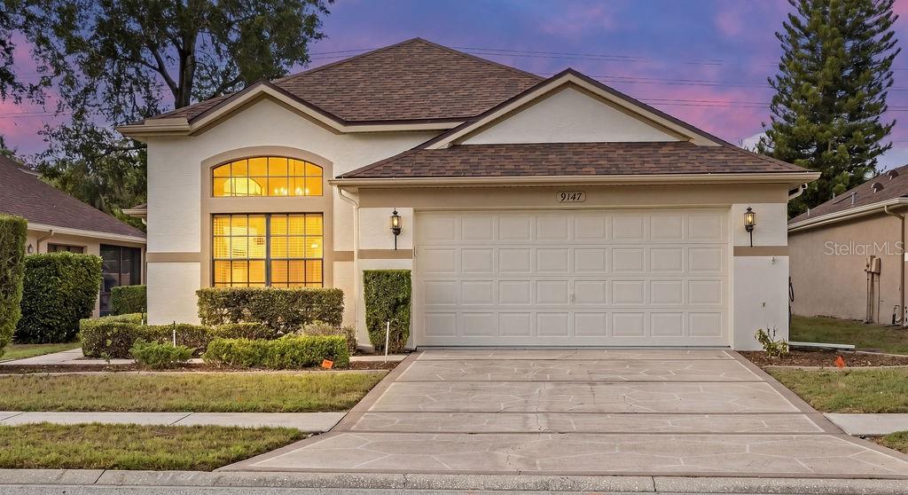 A single-story house with a beige stucco exterior, a two-car garage, and a manicured lawn — 9147 JIMINEZ DRIVE, HUDSON, FL