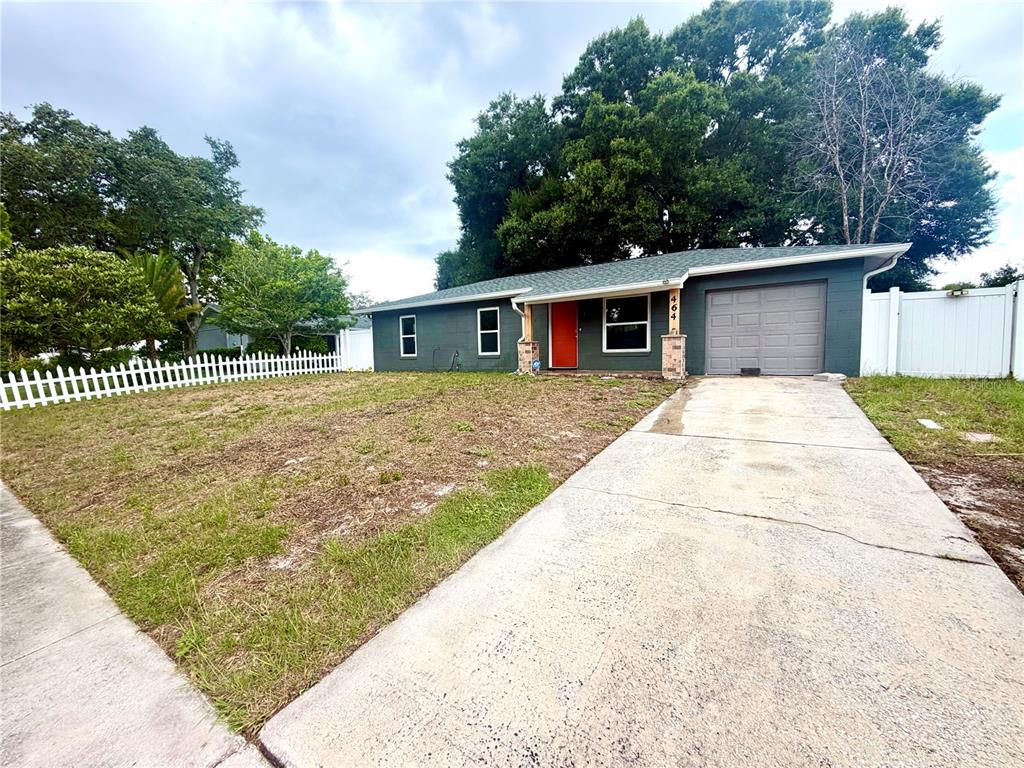 A single-story house with a dark green exterior, red front door, and attached garage — 464 NEW MEADOWS COURT, OCOEE, FL