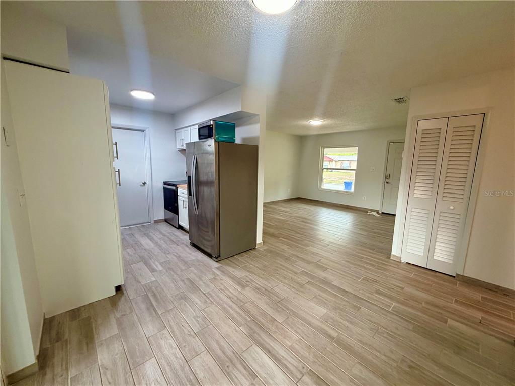 A kitchen with stainless steel appliances and wood-look tile flooring opens into a living area — 464 NEW MEADOWS COURT, OCOEE, FL