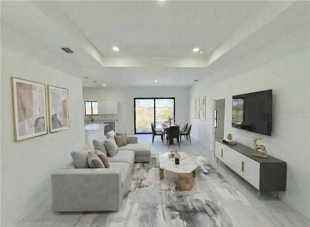 This virtually staged living room features a sectional sofa, a television, and a dining area — 4333 NW 34TH LANE, CAPE CORAL, FL