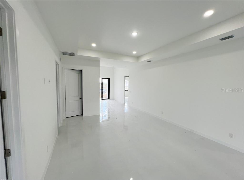 An empty room with white walls, glossy tile floors, and recessed ceiling lighting — 4333 NW 34TH LANE, CAPE CORAL, FL