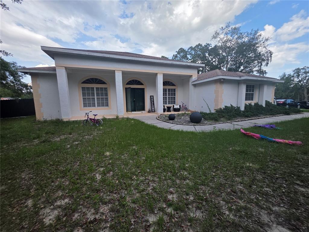 A single-story house with a covered front porch, columns, and a large front lawn — 17820 MONTEVERDE DRIVE, SPRING HILL, FL