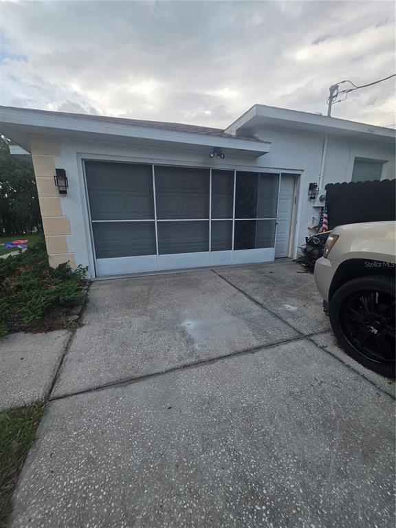 A concrete driveway leads to a garage with a white sliding screen door enclosure — 17820 MONTEVERDE DRIVE, SPRING HILL, FL