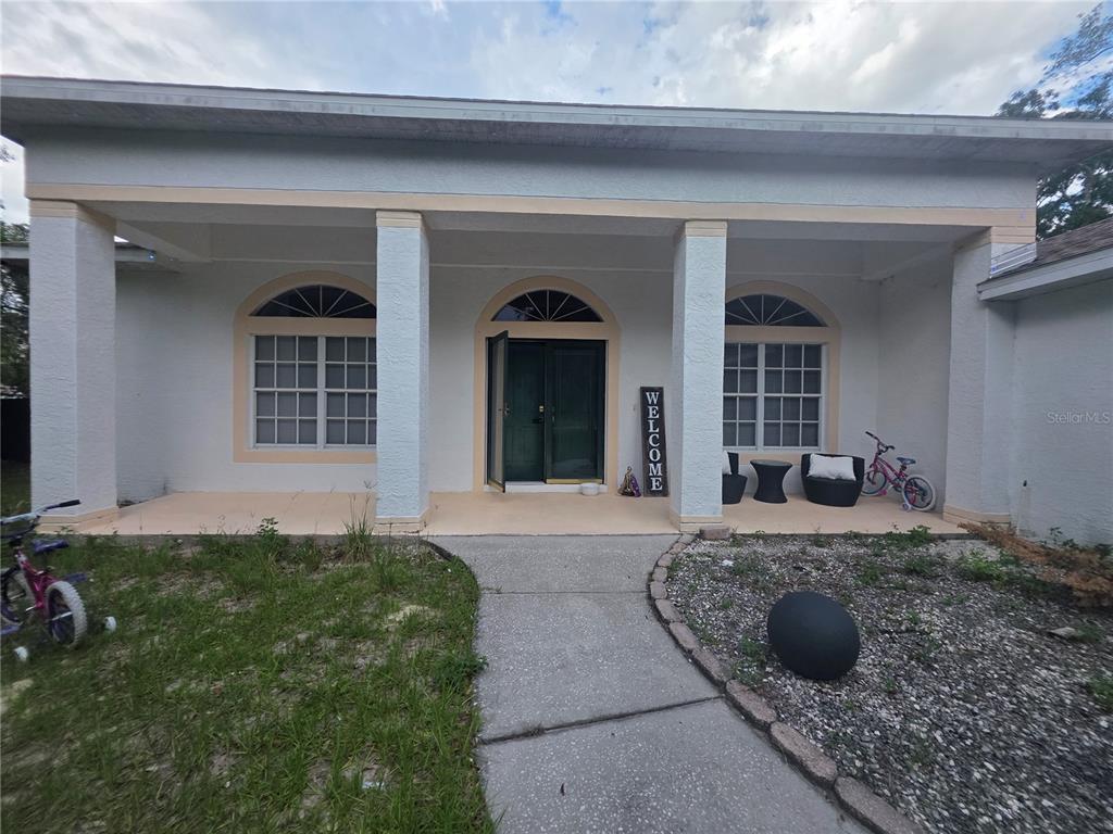 The exterior of a single-story house features a covered porch with three columns and arched windows — 17820 MONTEVERDE DRIVE, SPRING HILL, FL
