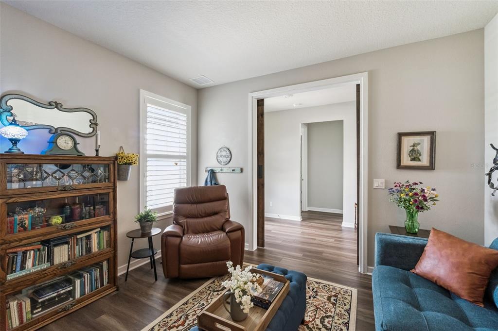 A cozy living room features a leather recliner, a wooden bookshelf, and a blue sofa — 2701 TIMBERGROVE STREET, ST CLOUD, FL