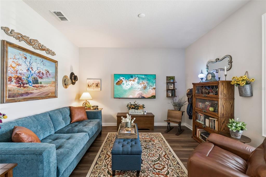 A living room features a blue sofa, a leather armchair, and a wall-mounted television — 2701 TIMBERGROVE STREET, ST CLOUD, FL