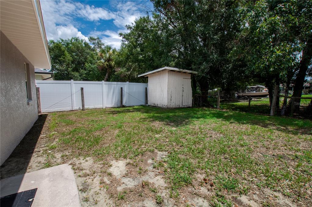 A backyard features a white vinyl fence, a small wooden shed, and patchy grass — 1204 E GIBSON STREET, ARCADIA, FL