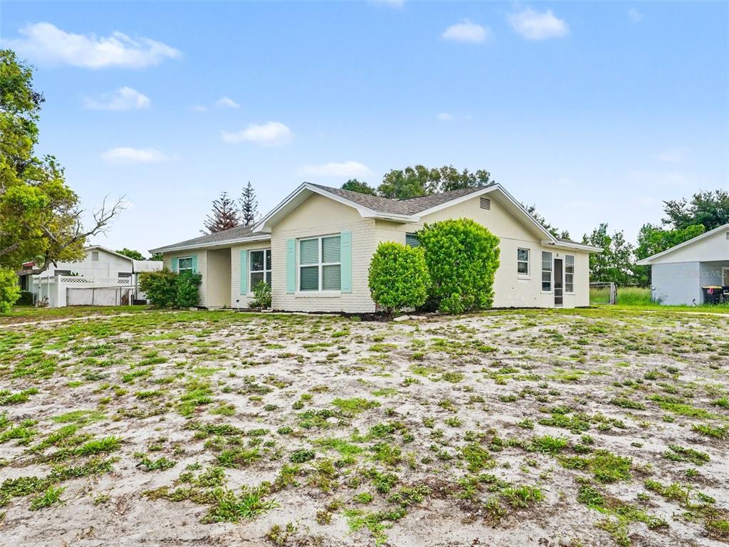 A light-colored, single-story house with a large, sandy front yard and green shutters — 308 VANIMAN AVENUE, WINTER HAVEN, FL