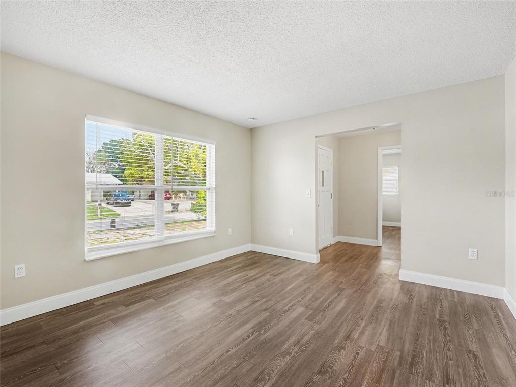 An empty room with light-colored walls, wood-look flooring, and a large window with blinds — 308 VANIMAN AVENUE, WINTER HAVEN, FL