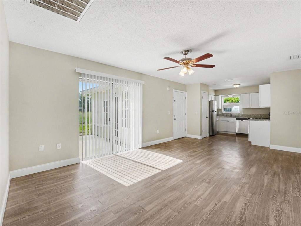 An open-concept living area features wood-look flooring, a ceiling fan, and a sliding glass door — 308 VANIMAN AVENUE, WINTER HAVEN, FL