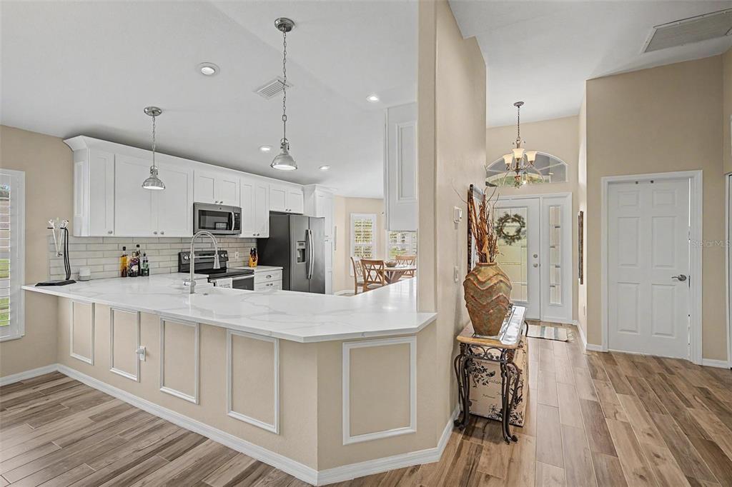 A kitchen with white cabinets, a quartz countertop island, and wood-look tile flooring — 1004 SWEET JASMINE DRIVE, TRINITY, FL