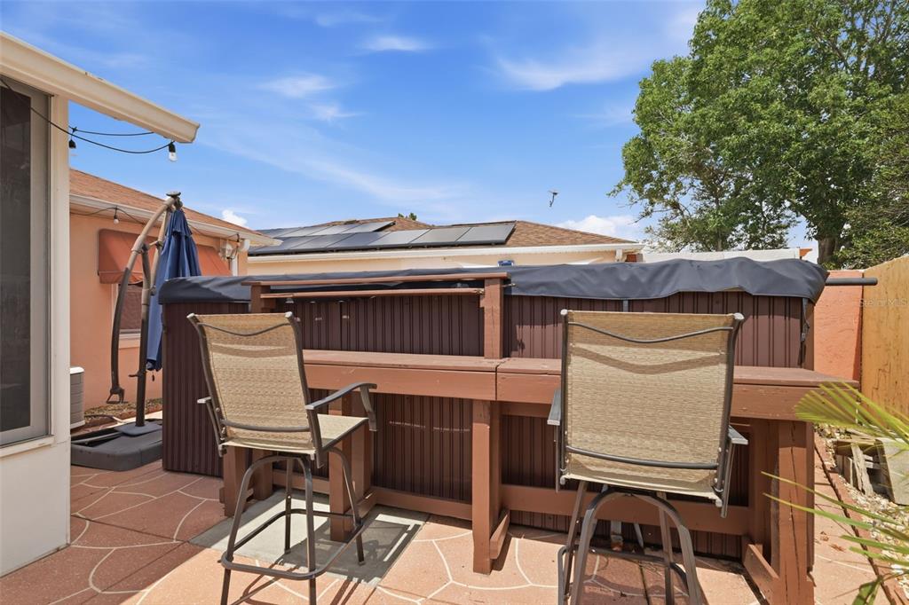 A patio features a hot tub enclosed by a wooden bar with two tall chairs — 1004 LAREDO LANE, LADY LAKE, FL