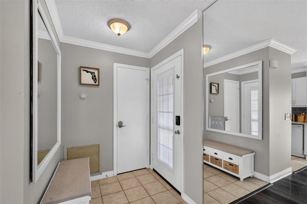 An entryway features tile flooring, a white bench, a mirror, and a front door — 1004 LAREDO LANE, LADY LAKE, FL