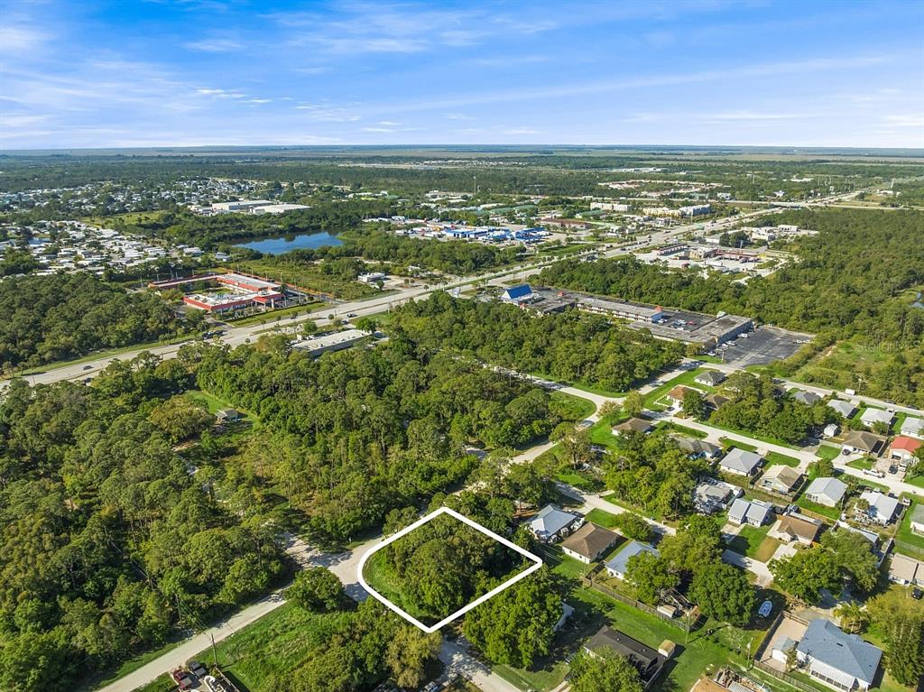 An aerial view shows a vacant, tree-covered lot outlined in white within a residential neighborhood — 2115 86TH DRIVE, VERO BEACH, FL