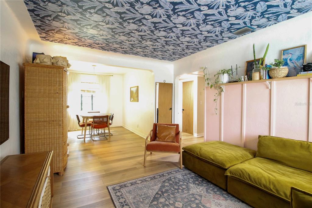 A living room with a patterned blue ceiling, pink wall paneling, and a green sofa — 3920 5TH AVENUE N, ST PETERSBURG, FL