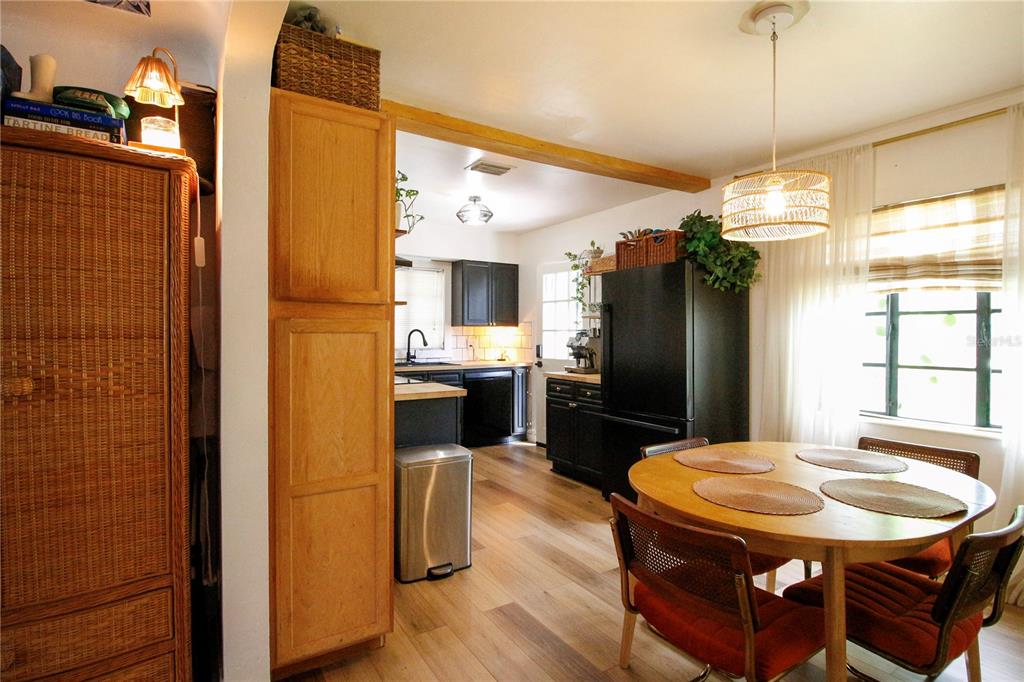 A dining area with a round wooden table leads into a kitchen with black cabinets — 3920 5TH AVENUE N, ST PETERSBURG, FL