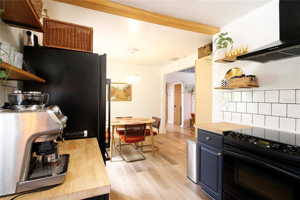 A kitchen with dark cabinets, wood countertops, and white subway tile opens into a dining area — 3920 5TH AVENUE N, ST PETERSBURG, FL
