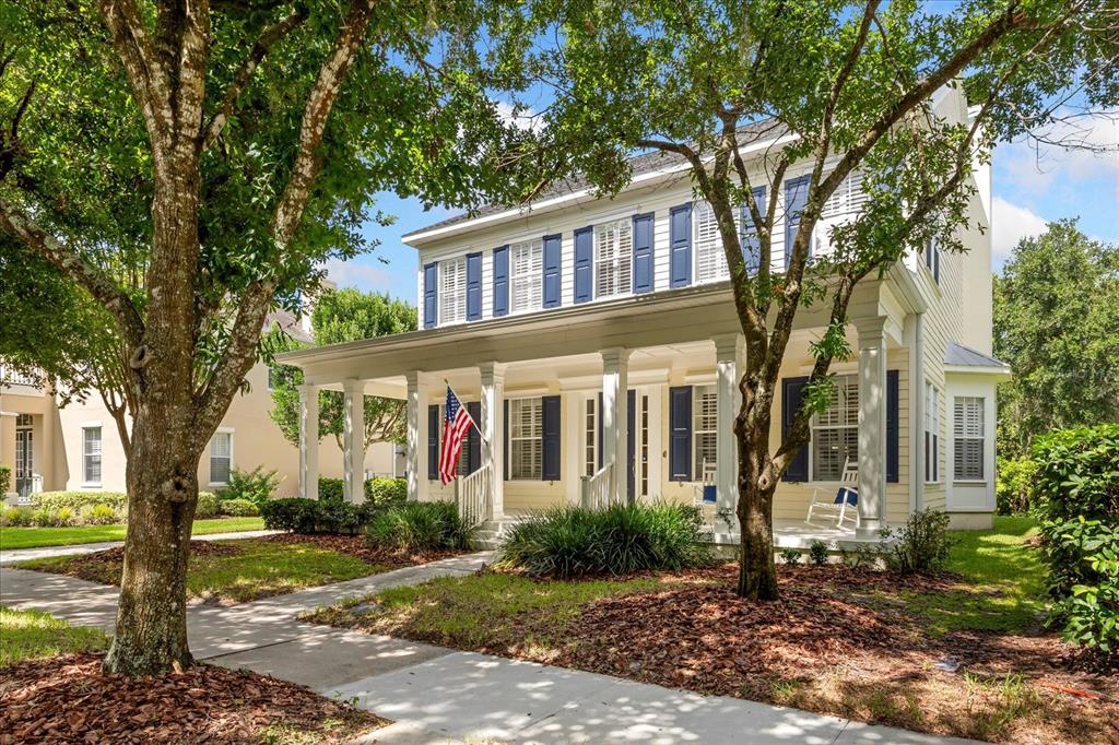 A two-story yellow house with blue shutters and a large front porch under trees — 915 JASMINE STREET, CELEBRATION, FL