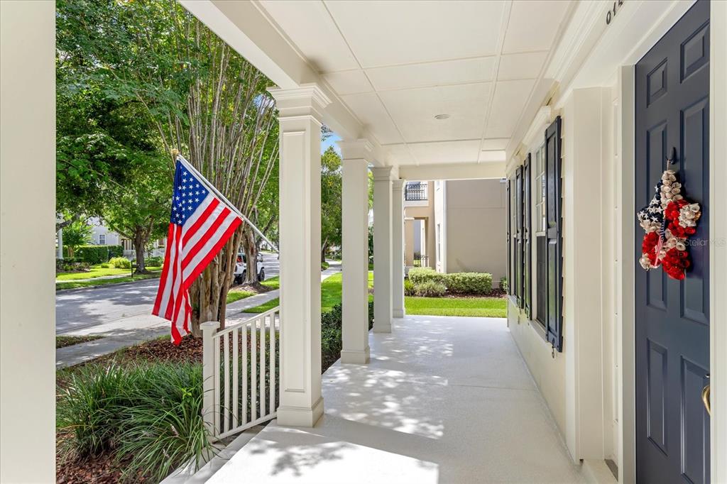 A covered front porch features white columns, a dark blue door, and an American flag — 915 JASMINE STREET, CELEBRATION, FL