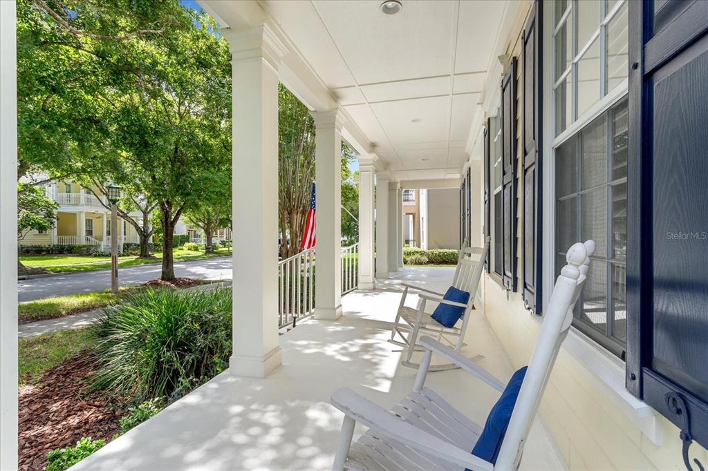 A covered front porch features white columns, two rocking chairs, and views of a street — 915 JASMINE STREET, CELEBRATION, FL